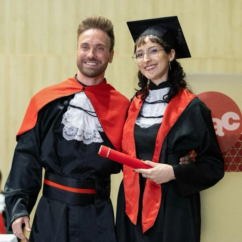 Ana na formatura de Design, de beca e capelo, segurando o diploma